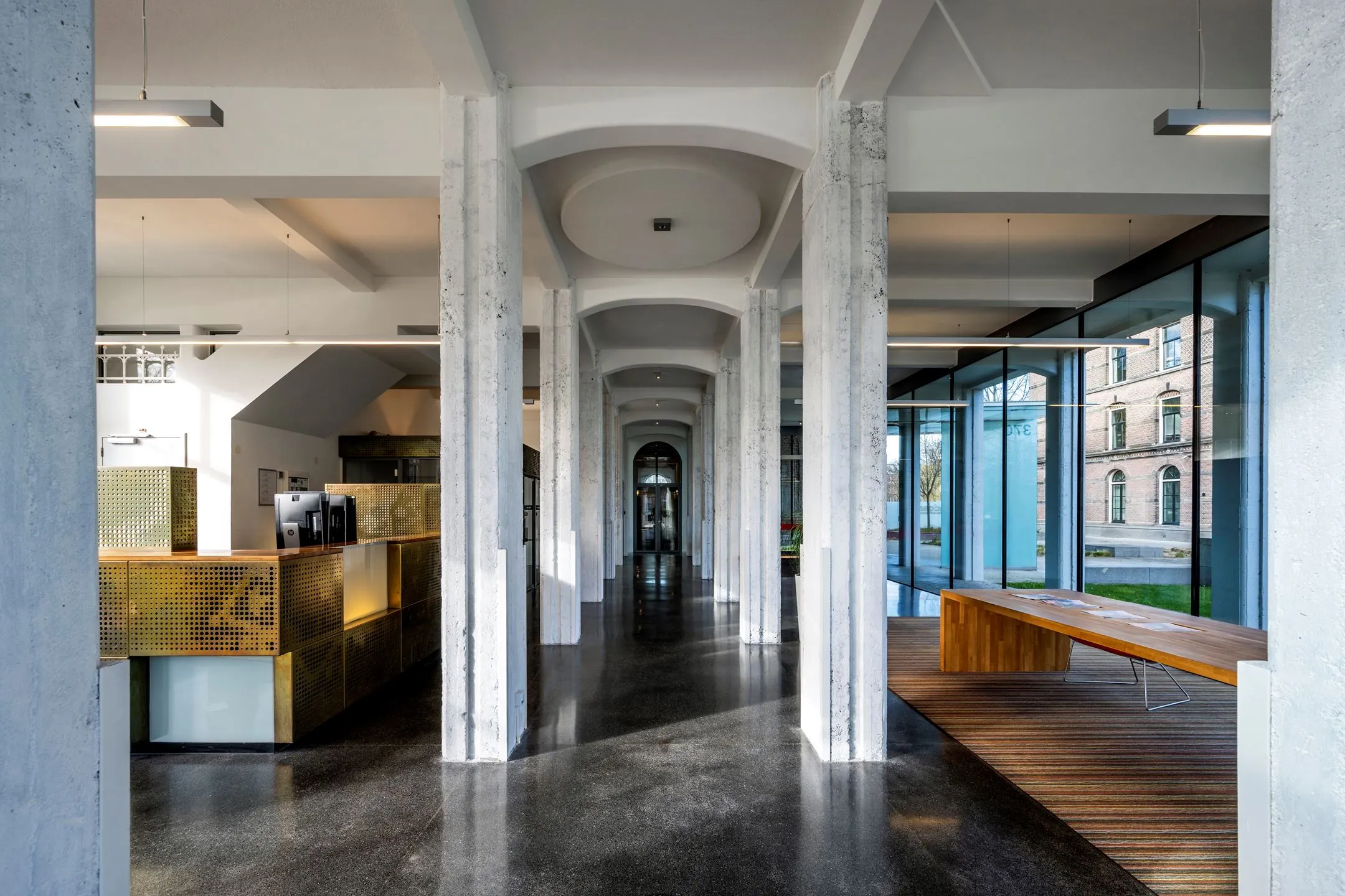 Moderne kantoorruimte met hoge ramen, betonnen pilaren en een stijlvolle ontvangstbalie in De Bell aan de Sarphatistraat 370.