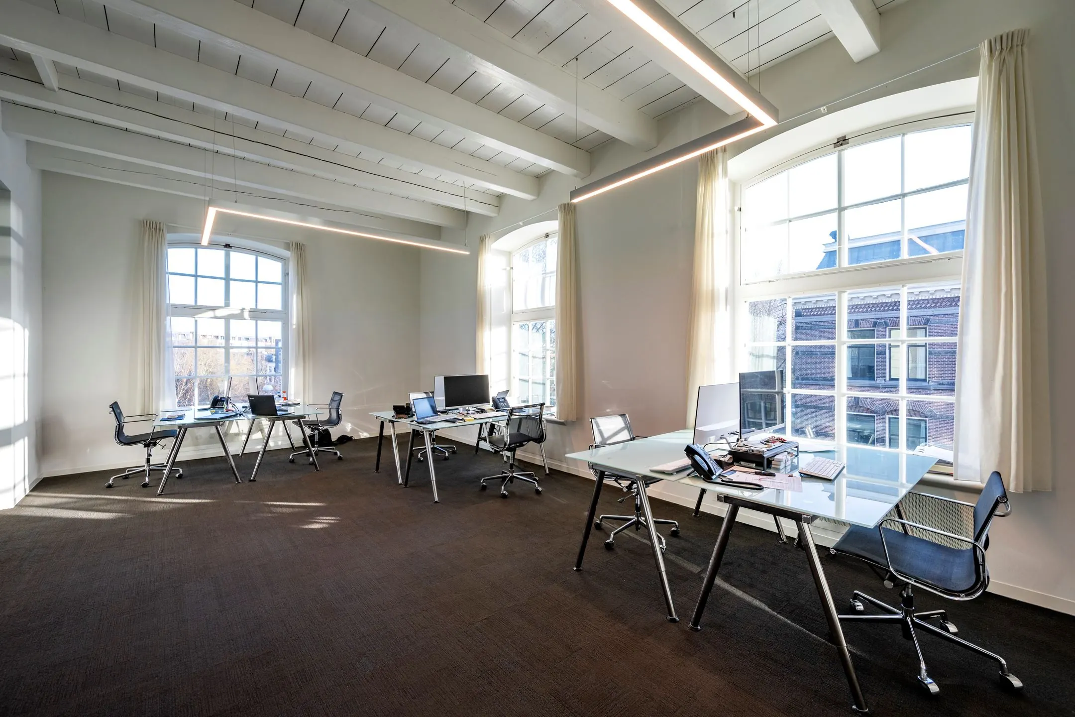 Lichte en moderne kantoorruimte met glazen bureaus en hoge ramen aan de Sarphatistraat 370 in De Bell.