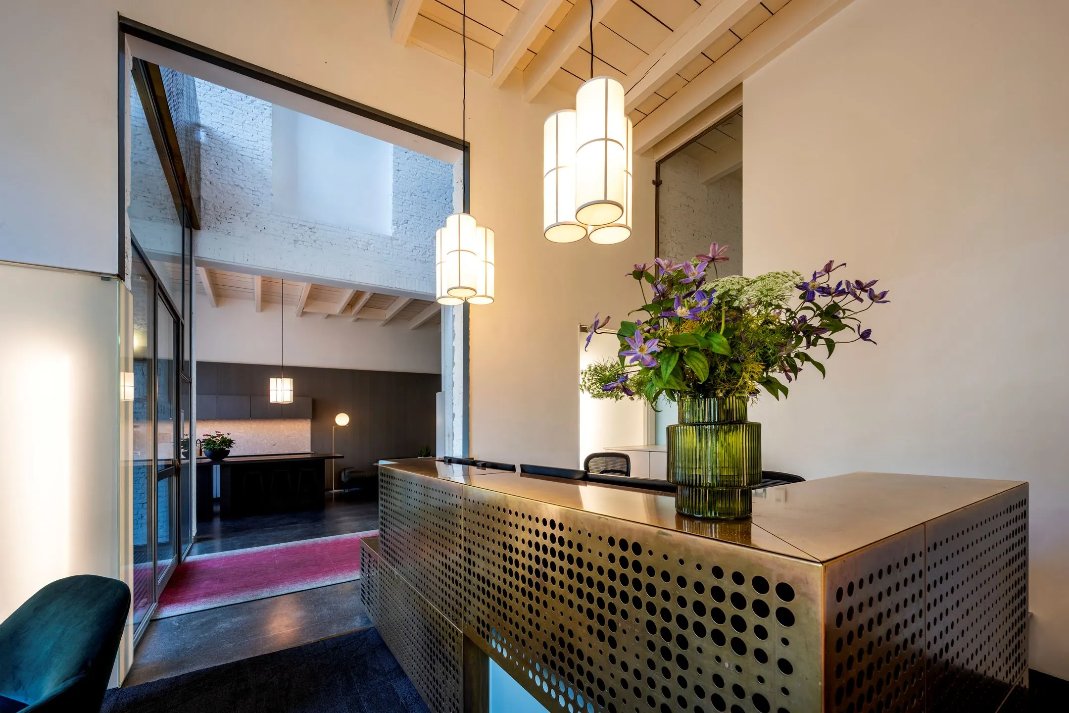 Moderne entree met receptiebalie, designverlichting en bloemstuk in kantoorgebouw De Bell aan de Sarphatistraat 370.
