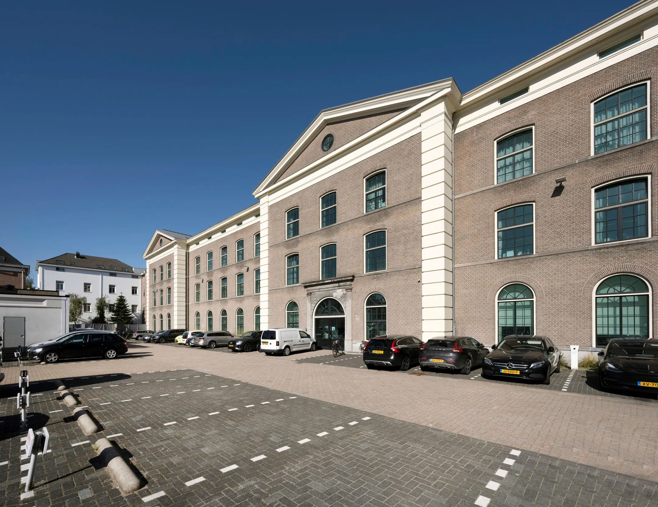 Vooraanzicht van het kantoorgebouw De Bell aan de Sarphatistraat 370 met parkeerplaatsen op de voorgrond.