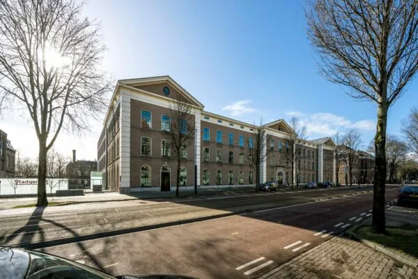 Vooraanzicht van kantoorpand De Bell aan de Sarphatistraat 370 in Amsterdam op een zonnige dag.