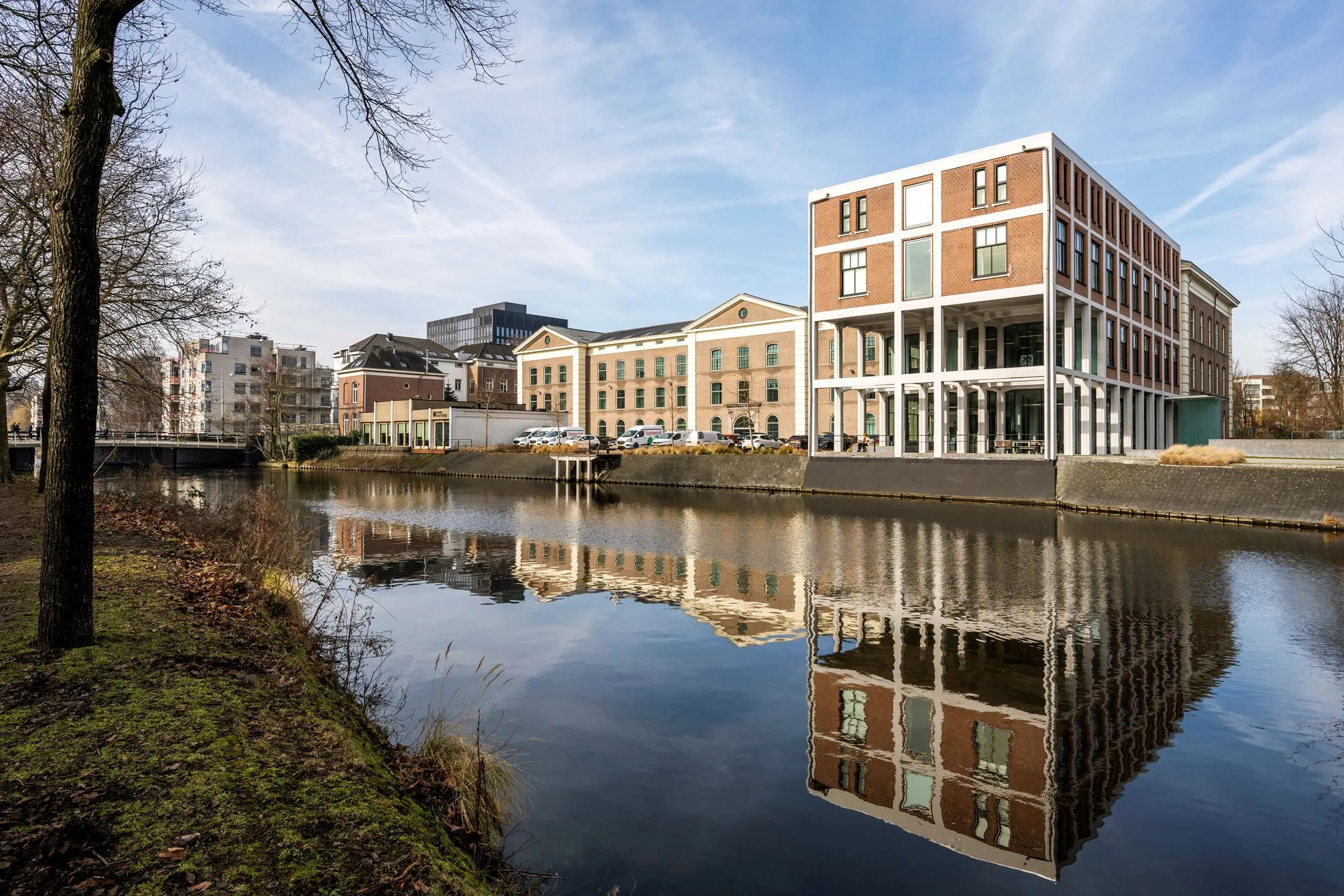Modern kantoorpand De Bell aan de Sarphatistraat 370-20 weerspiegeld in het water van de naastgelegen gracht.