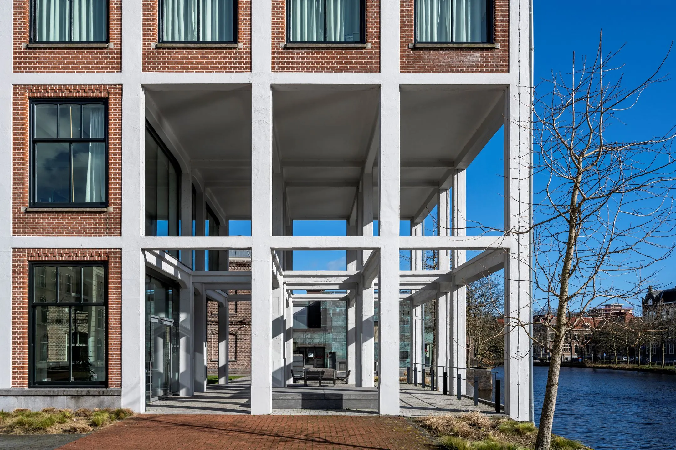 Moderne kantoorruimte te huur in De Bell aan de Sarphatistraat 370, met transparante gevel en uitzicht op het water.