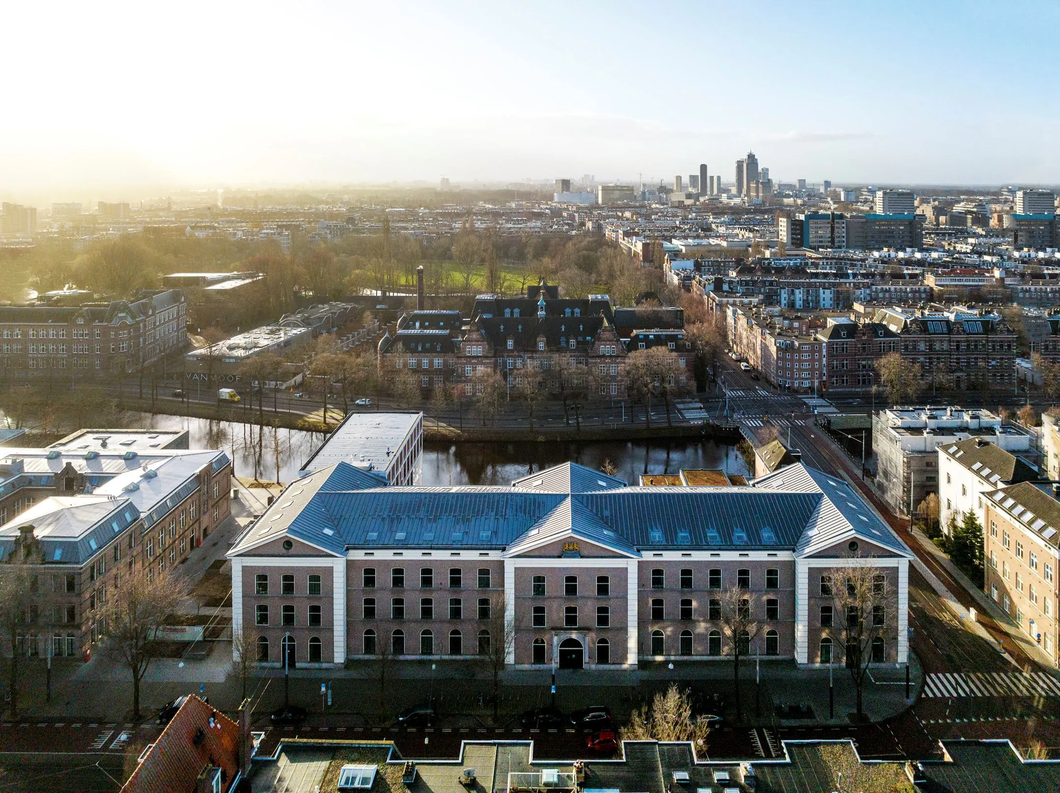 Luchtfoto van het kantoorgebouw De Bell aan de Sarphatistraat 370-23 in Amsterdam, met uitzicht op de stad.