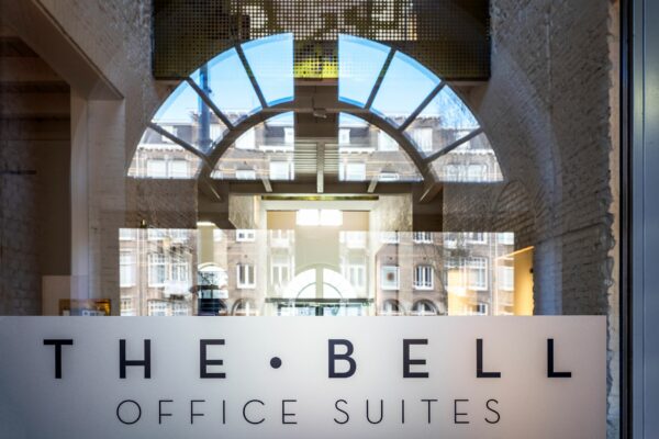 Glazen entree met logo van The Bell Office Suites aan de Sarphatistraat 370 in Amsterdam.