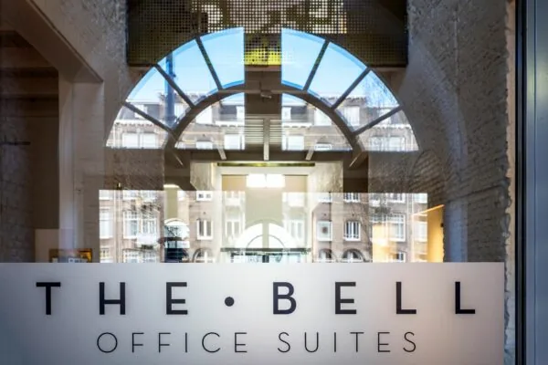 Glazen entree met logo van The Bell Office Suites aan de Sarphatistraat 370 in Amsterdam.