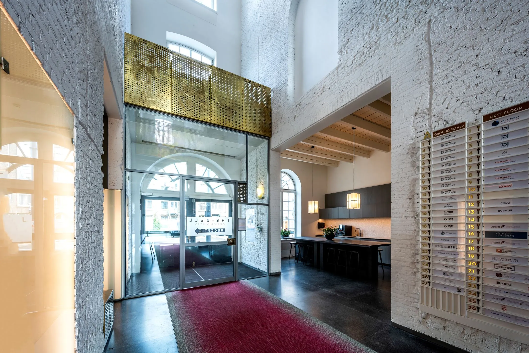 Entreehal van kantoorruimte De Bell aan de Sarphatistraat 370 met hoge plafonds, moderne receptie en bedrijfsnaambord.