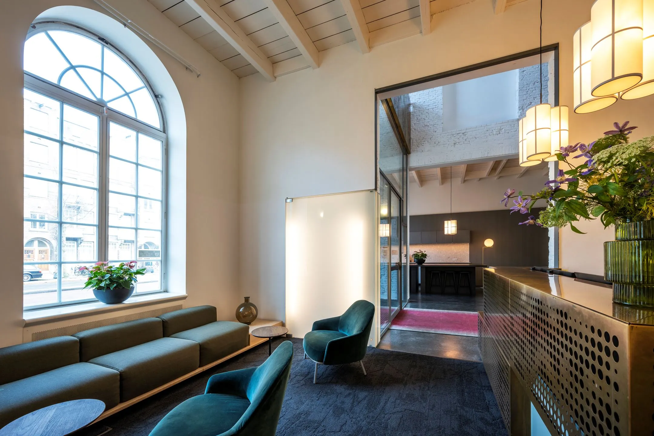 Moderne en stijlvolle entree van kantoorruimte De Bell aan de Sarphatistraat 370 met zitgedeelte, receptiebalie en hoge ramen.