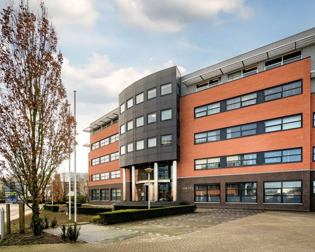 Moderne kantoorruimte te huur aan De Waal 18, in een rood-bruin gebouw met zwarte accenten en grote ramen.
