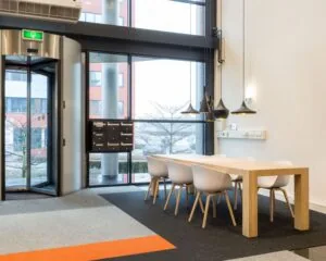 Moderne kantoorruimte met houten vergadertafel, witte stoelen en grote ramen in De Waal 18.