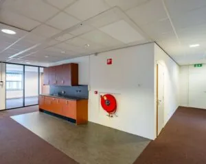 Kantoorruimte met pantry, brandslanghaspel en doorgang naar vergaderruimte in De Waal 18.