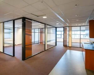 Moderne kantoorruimte te huur aan De Waal 18 met glazen scheidingswanden, tapijtvloer en kitchenette.