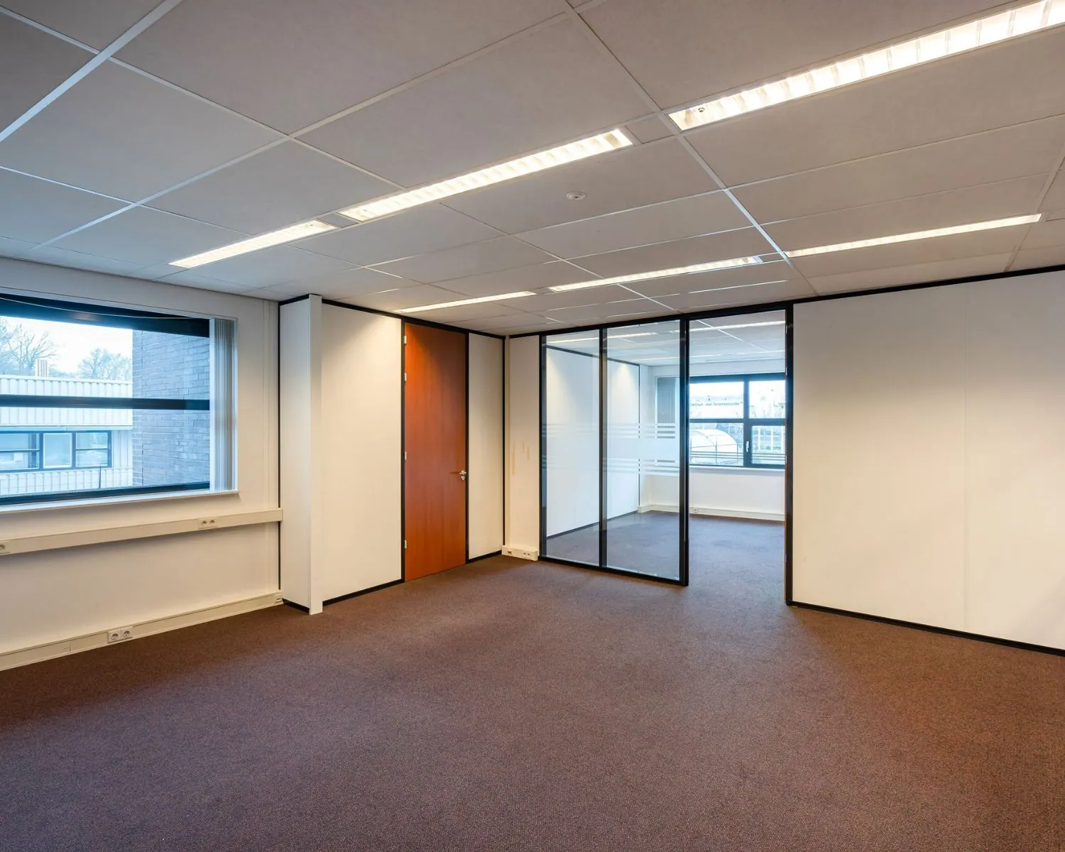 Moderne, lege kantoorruimte te huur aan De Waal 18, met glazen scheidingswand en ingebouwde verlichting.