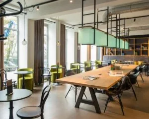 Moderne kantoorruimte aan de President Kennedylaan 19 in Den Haag met grote ramen, designmeubilair en een lange houten vergadertafel.