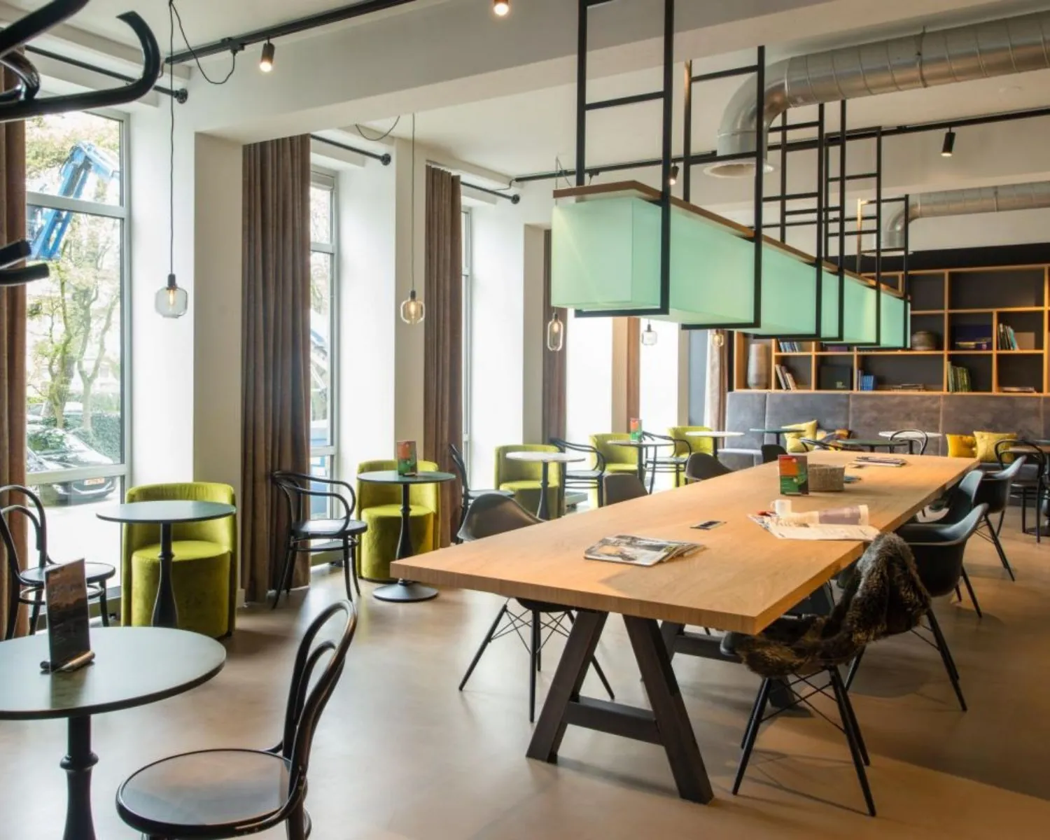 Moderne kantoorruimte aan de President Kennedylaan 19 in Den Haag met grote ramen, designmeubilair en een lange houten vergadertafel.