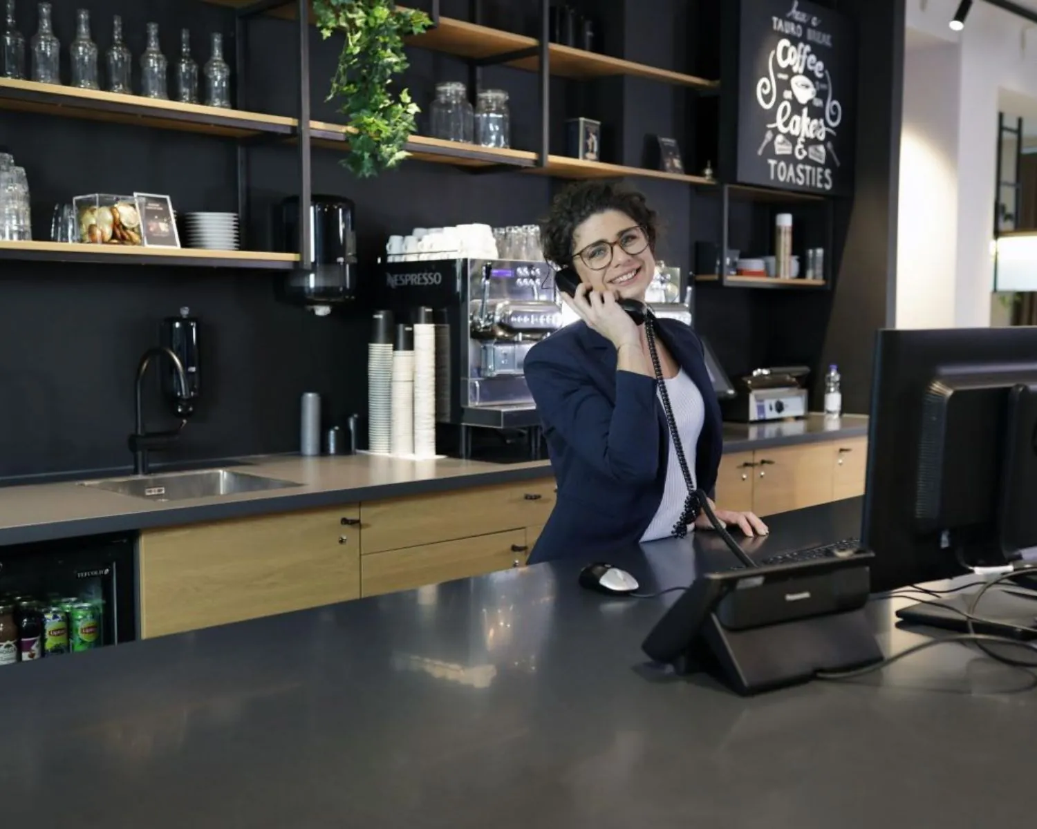 Receptioniste aan het werk bij de koffiecorner in een moderne kantoorruimte aan de President Kennedylaan 19 in Den Haag.