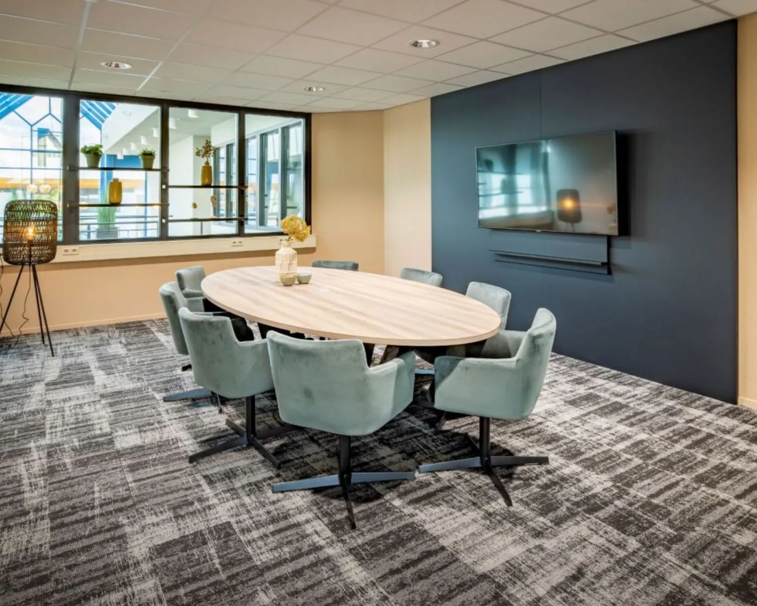 Moderne vergaderruimte met ovale tafel, zachte stoelen en een grote muurtelevisie in een kantoor aan de Europalaan 4 in Den Bosch.