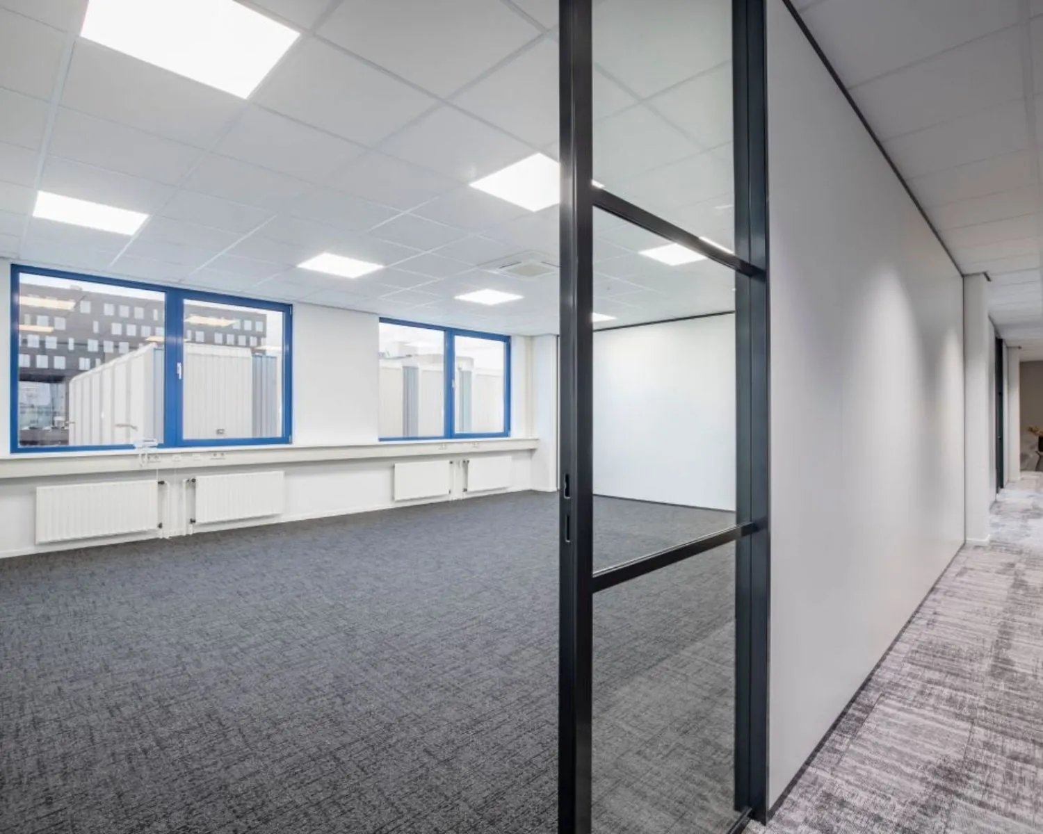 Moderne, lichte kantoorruimte met grijze vloerbedekking en grote ramen aan de Europalaan 4 in Den Bosch.