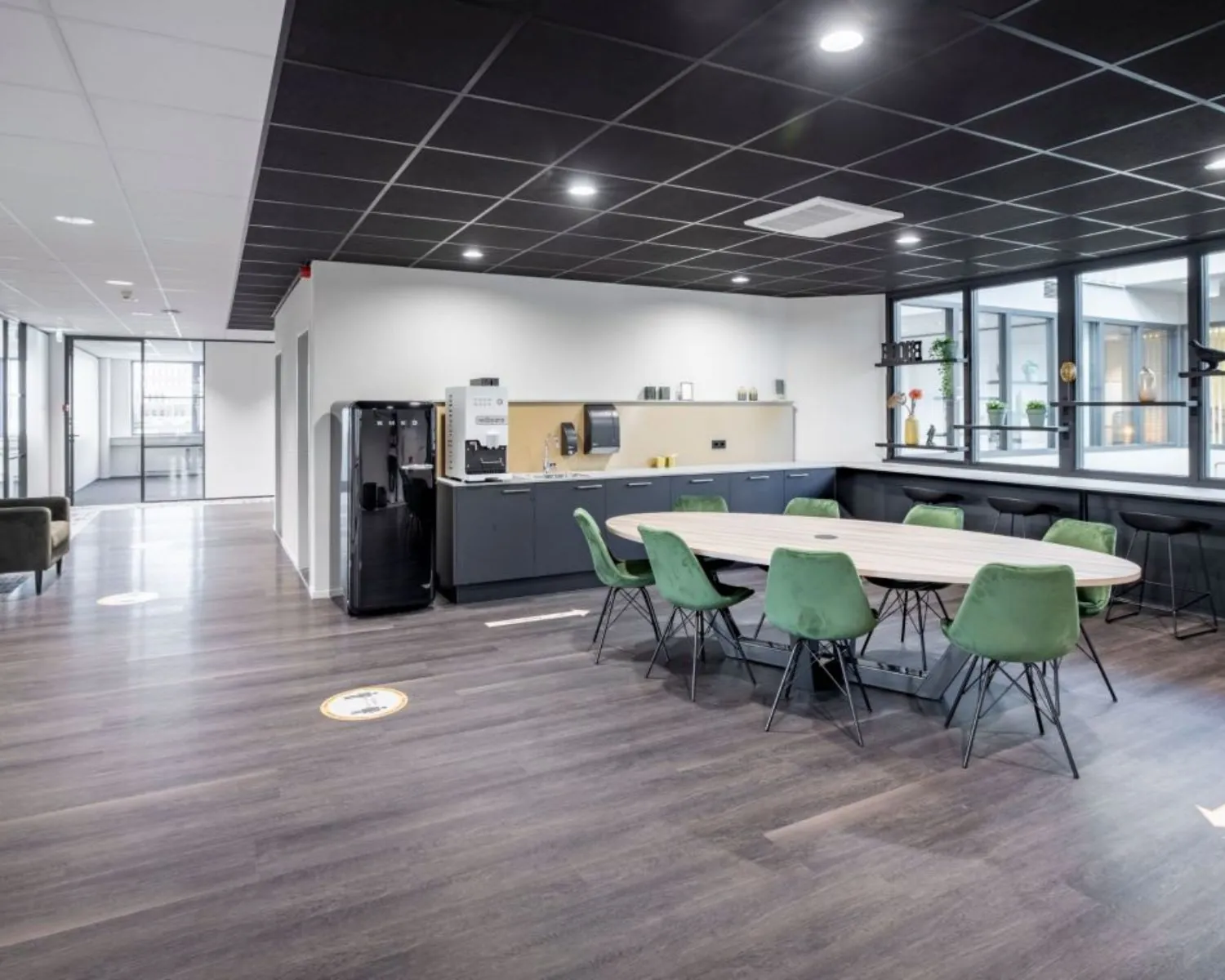 Moderne kantoorruimte met een open keuken, ovale vergadertafel en groene stoelen aan de Europalaan 4 in Den Bosch.