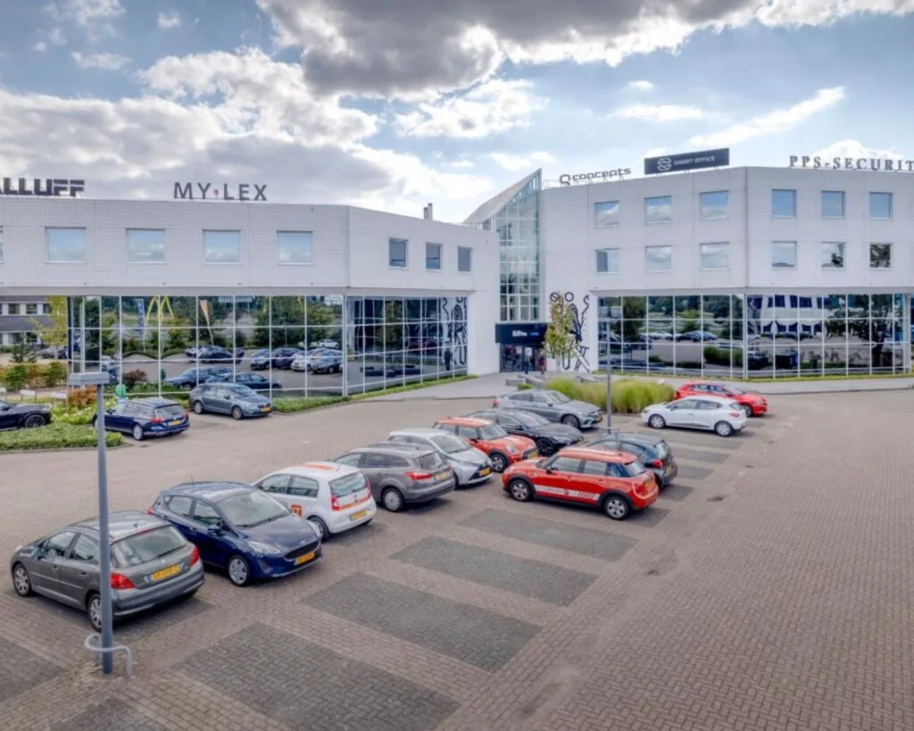 Moderne kantoorruimte aan de Europalaan 6 in Den Bosch met parkeergelegenheid en bedrijfsnamen zichtbaar op de gevel.