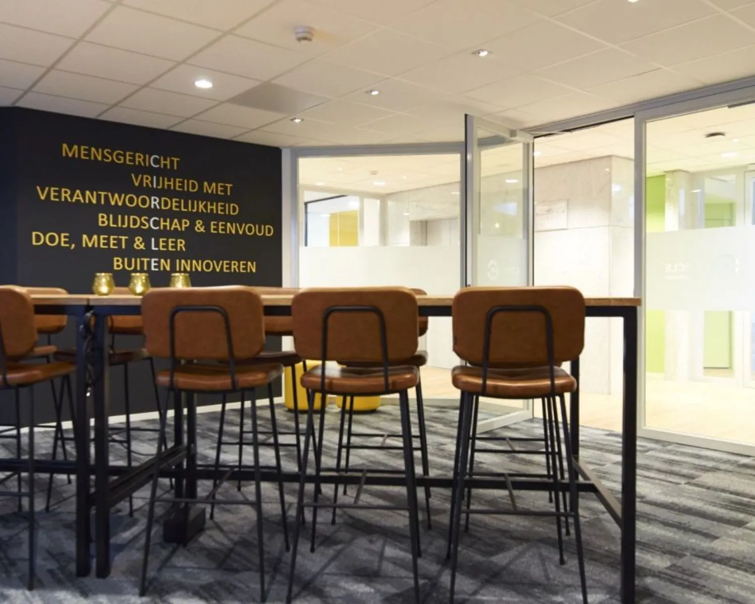 Moderne vergaderruimte met hoge stoelen, glazen wanden en inspirerende tekst op de muur in Fellenoord 200-240, Eindhoven.