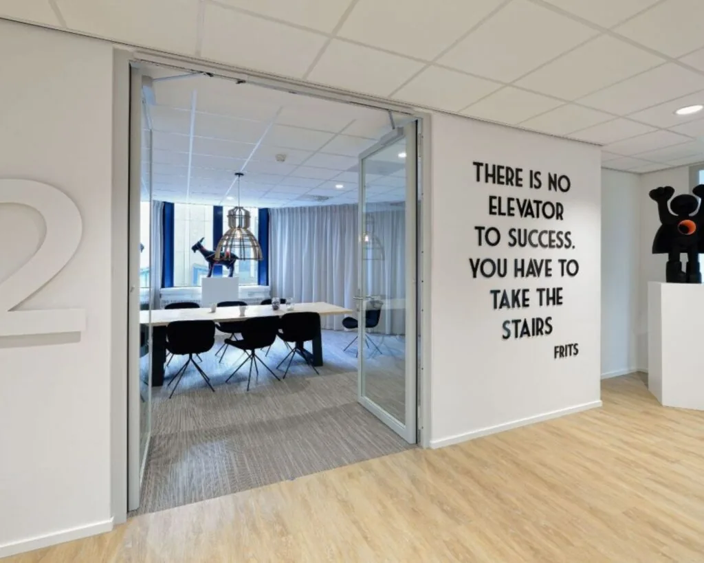 Moderne kantoorruimte in Eindhoven met vergaderruimte, kunstobjecten en een motiverende quote op de muur.