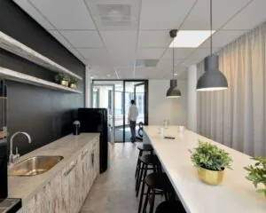 Moderne kitchenette met hoge tafel en barkrukken in een kantoorruimte aan Fellenoord 200-240 in Eindhoven.
