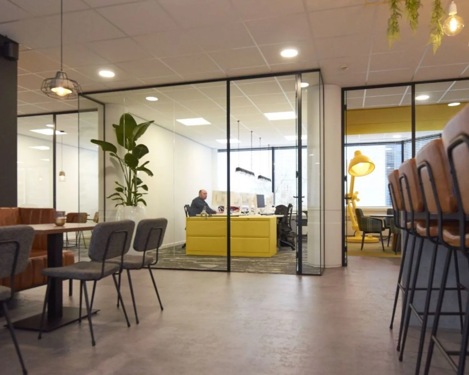 Moderne kantoorruimte te huur aan Fellenoord 200-240 in Eindhoven met glazen wanden, gele bureaus en een open zithoek.