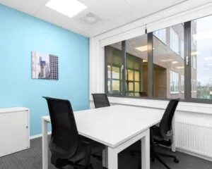 Moderne, lichte kantoorruimte te huur aan Het Rietveld 55A met witte bureaus, zwarte stoelen en grote ramen.