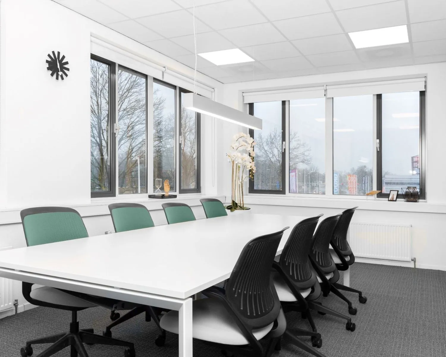 Moderne vergaderruimte met lange witte tafel, ergonomische stoelen en grote ramen in kantoor Het Rietveld 55A.