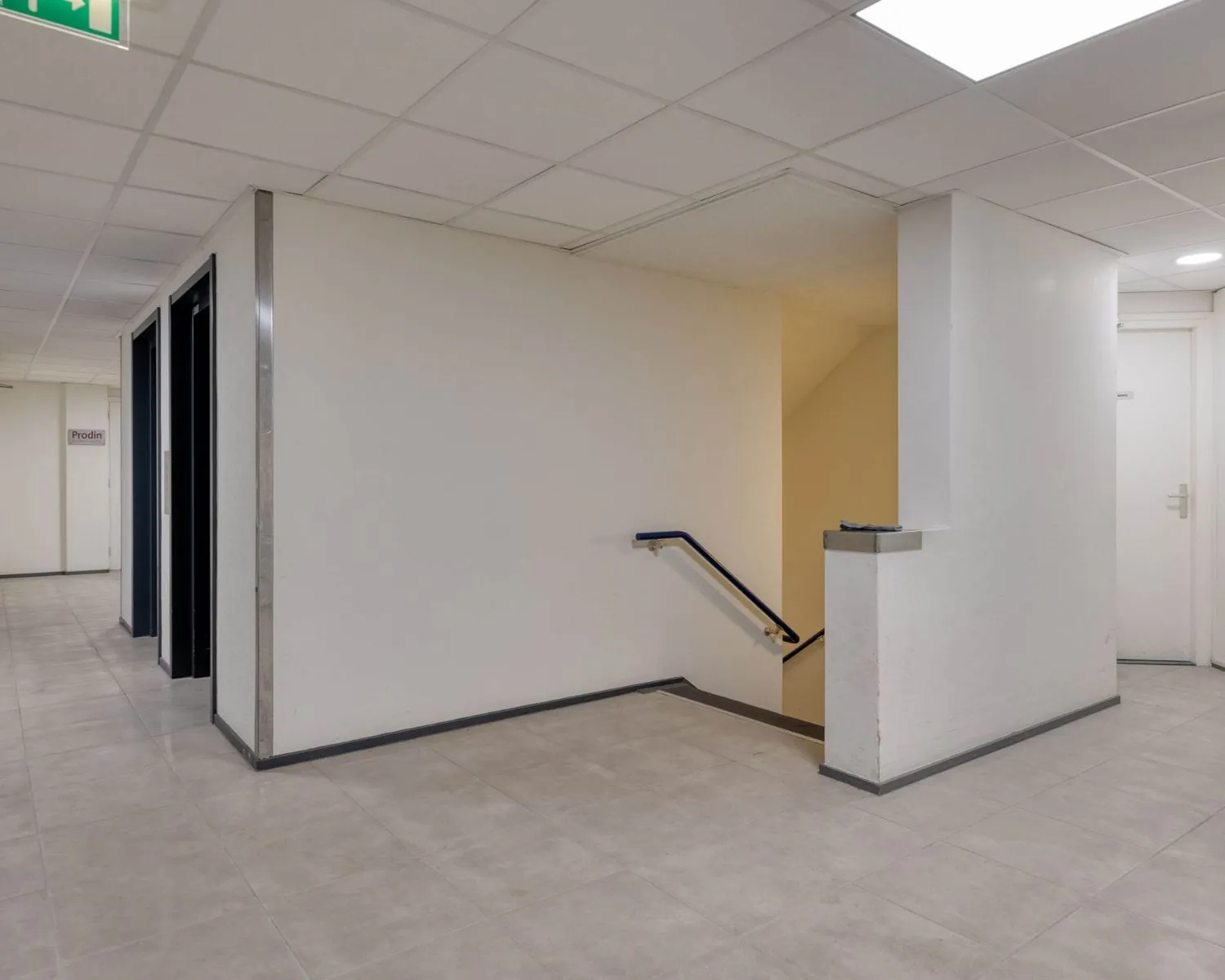 Zicht op een nette, gemeenschappelijke gang met trap en meerdere deuren in een kantoorruimte aan de Franciscusweg 219 in Hilversum.