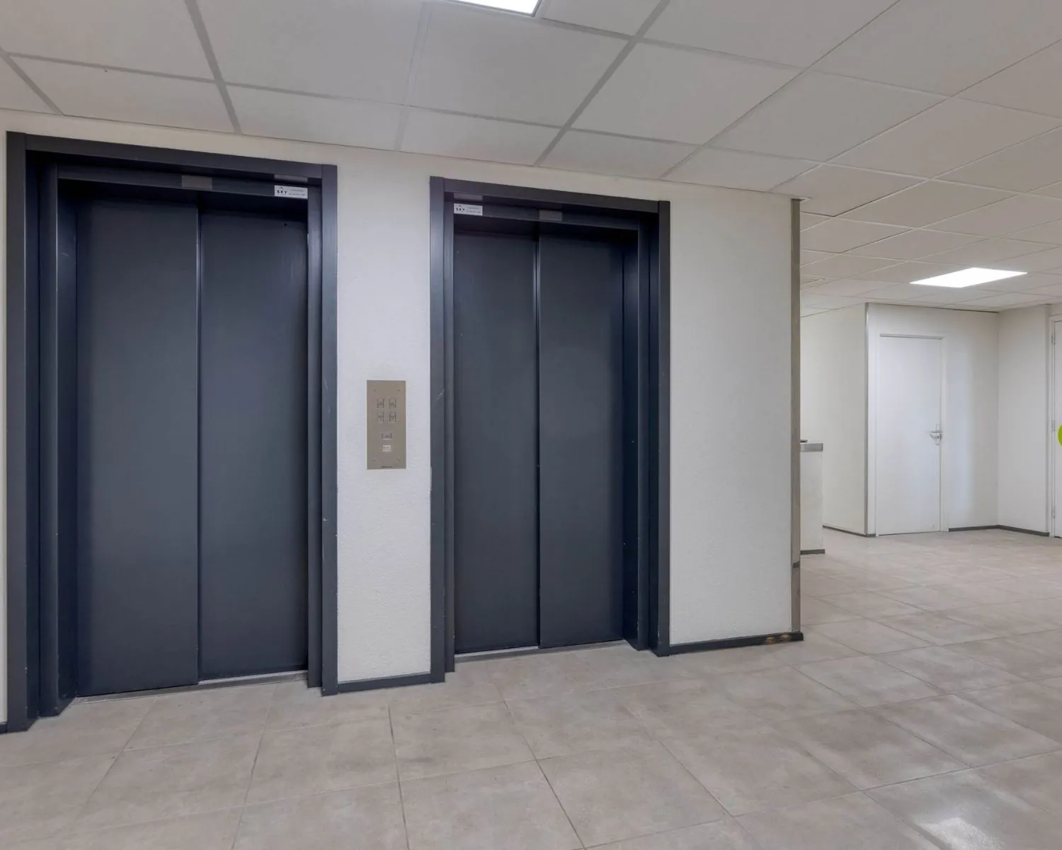 Twee gesloten liften in de hal van een modern kantoorpand aan de Franciscusweg 219 in Hilversum.