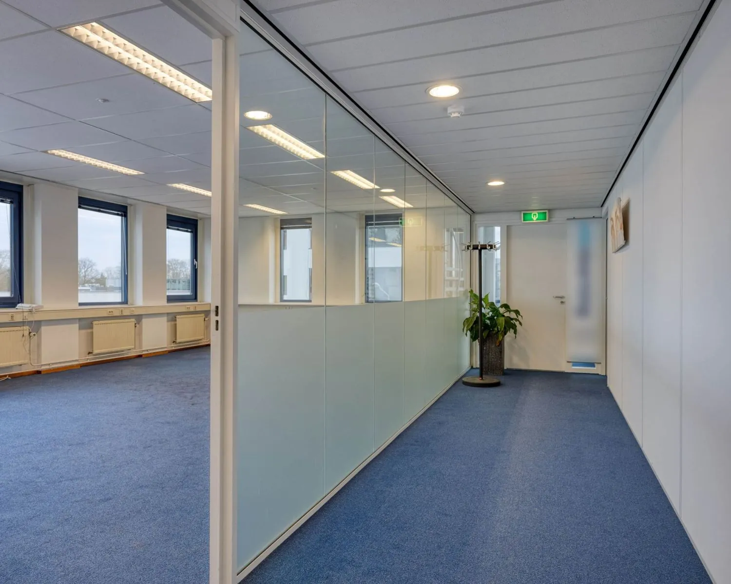 Moderne kantoorruimte met blauwe vloerbedekking en glazen scheidingswanden aan de Franciscusweg 219 in Hilversum.