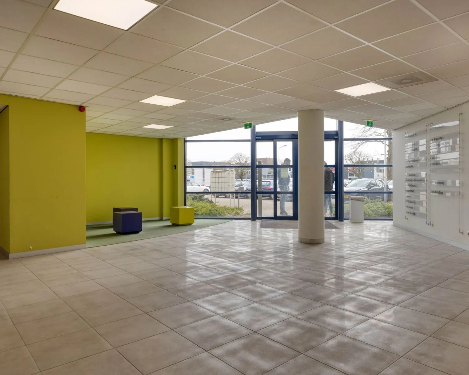 Ingangshal van een kantoorruimte aan de Franciscusweg 219 in Hilversum met tegelvloer, zitmeubels en grote ramen.