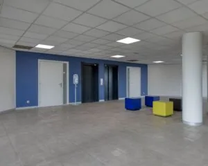 Moderne entreehal van een kantoorpand aan de Franciscusweg 219 in Hilversum met liften, zitblokken en blauwe accentmuur.