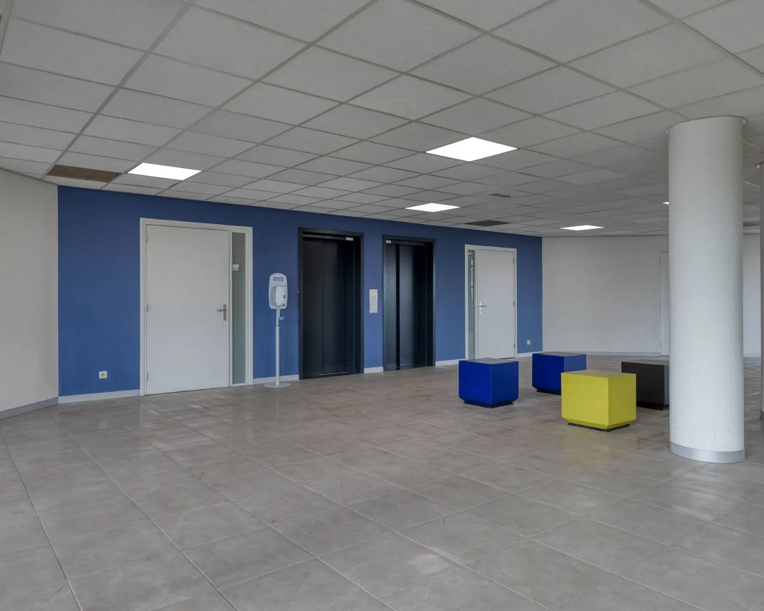 Moderne entreehal van een kantoorpand aan de Franciscusweg 219 in Hilversum met liften, zitblokken en blauwe accentmuur.