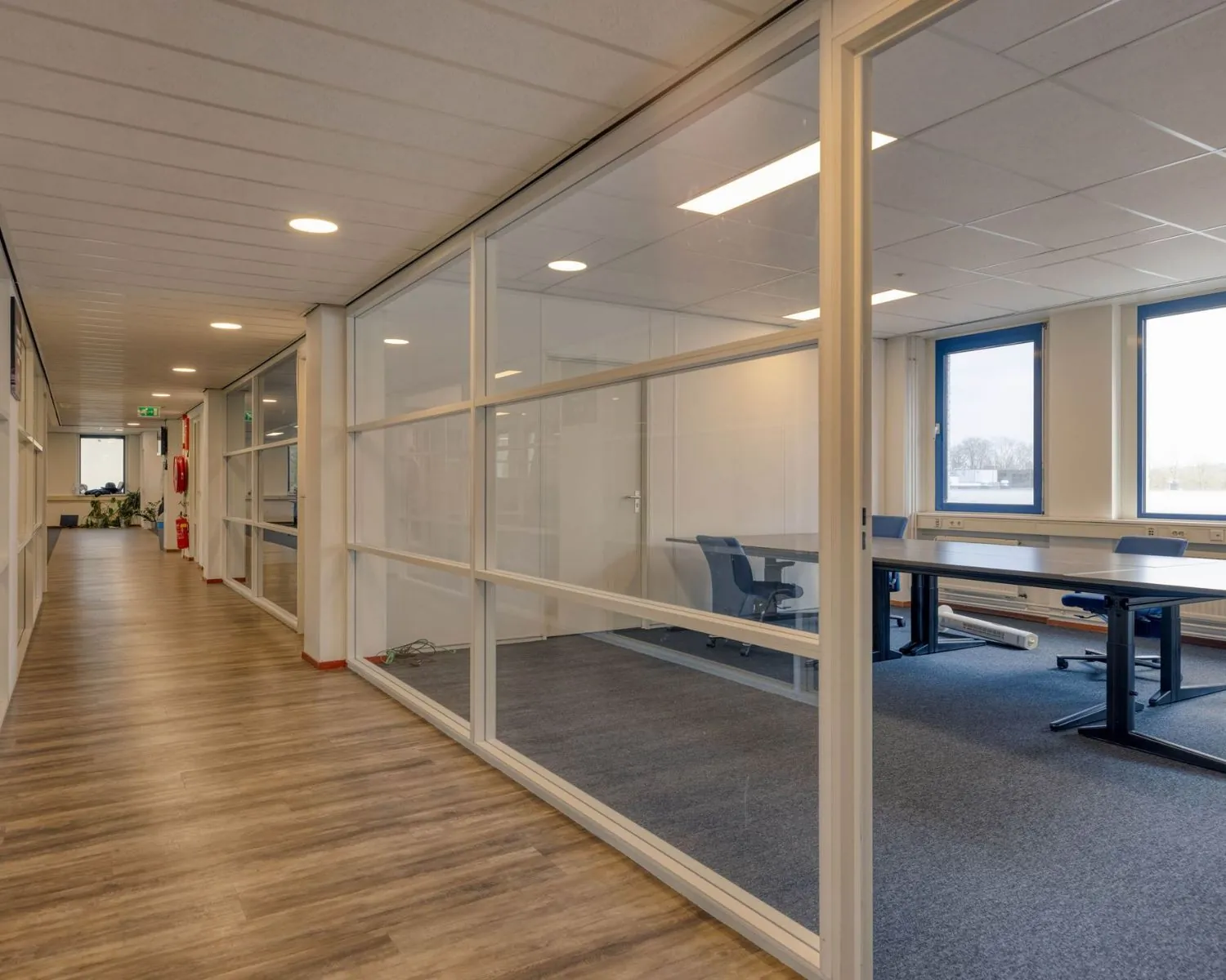 Moderne kantoorruimte met glazen wanden en houten vloer aan de Franciscusweg 219 in Hilversum.