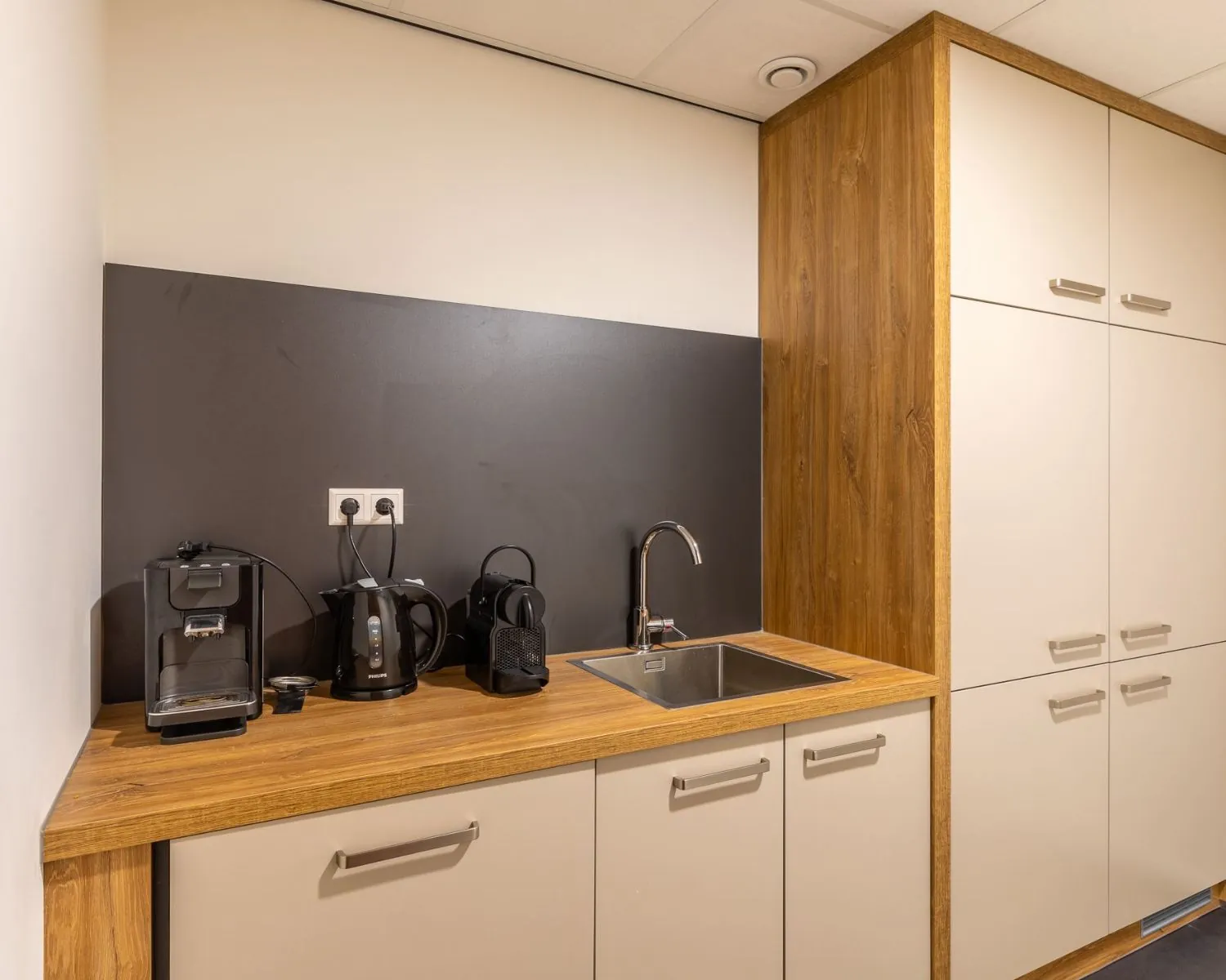Moderne kantoorpantry aan de Mozartlaan 27 in Hilversum met houten aanrechtblad, spoelbak en diverse koffieapparaten.