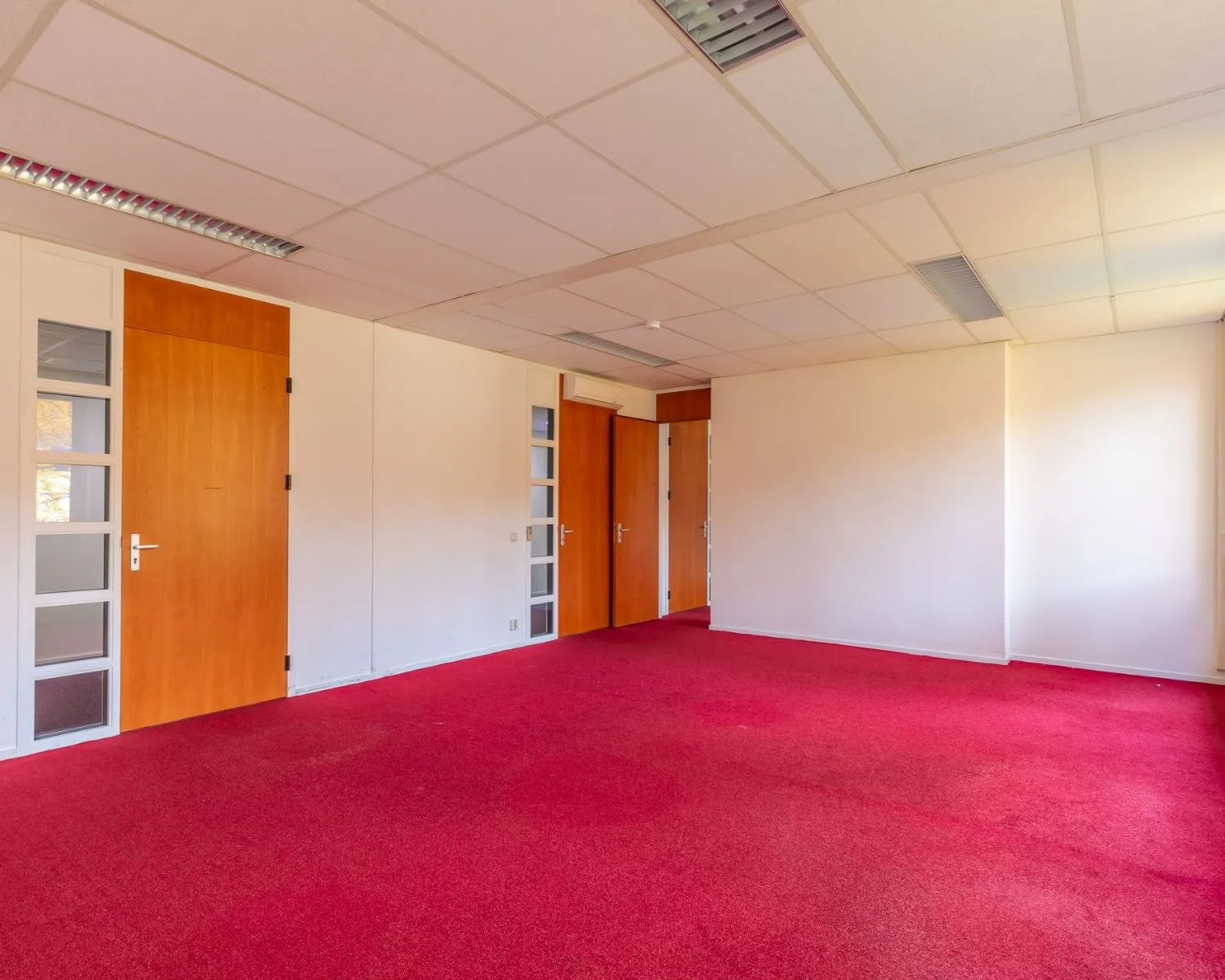 Leegstaande kantoorruimte met rode vloerbedekking aan de Mozartlaan 27 in Hilversum.