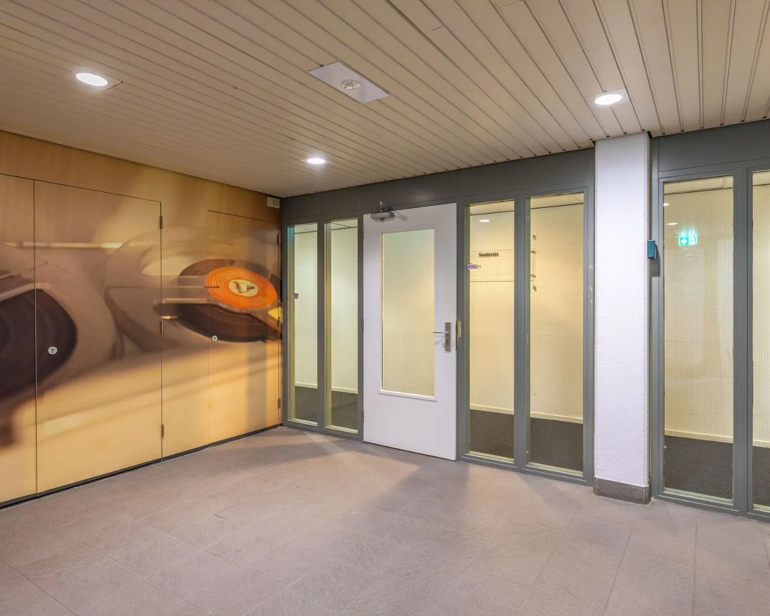 Entree van een kantoorruimte aan de Mozartlaan 27 in Hilversum met glazen deuren en een muurdecoratie met een platenspeler.