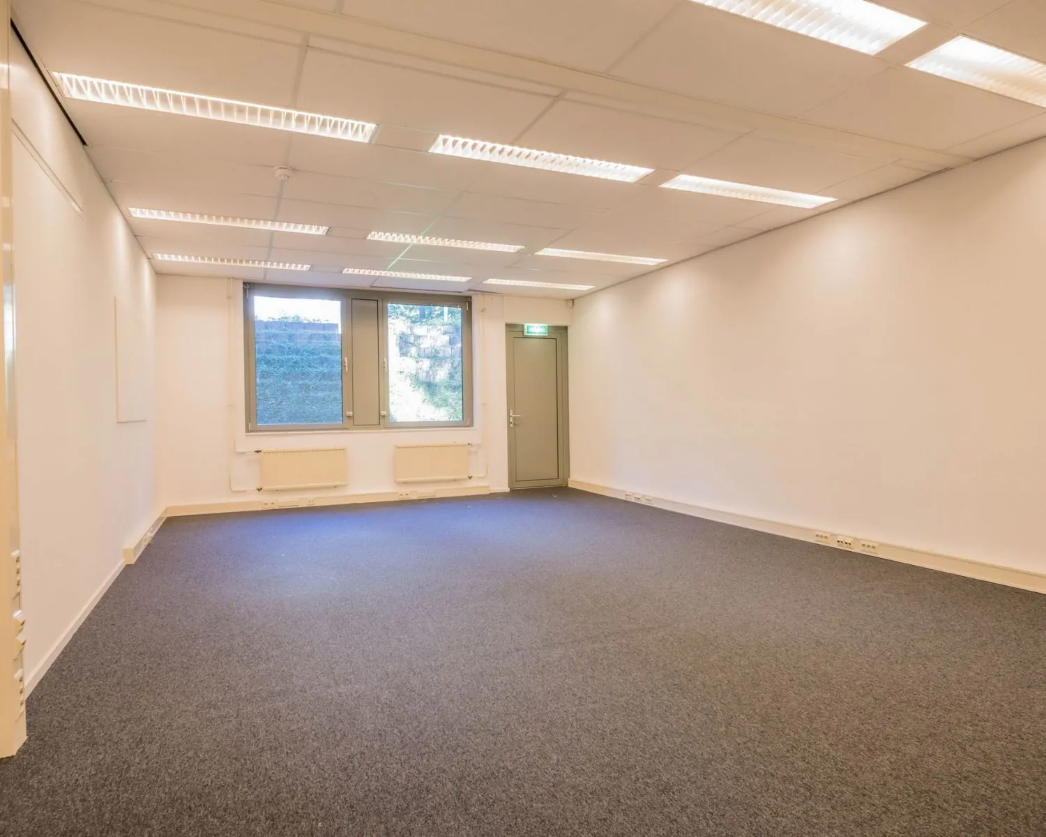 Leegstaande kantoorruimte met tapijtvloer en systeemplafond aan de Mozartlaan 27 in Hilversum.