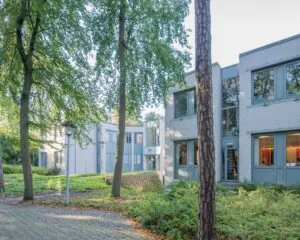 Moderne kantoorruimte aan de Mozartlaan 27 in Hilversum, omgeven door groen en hoge bomen.