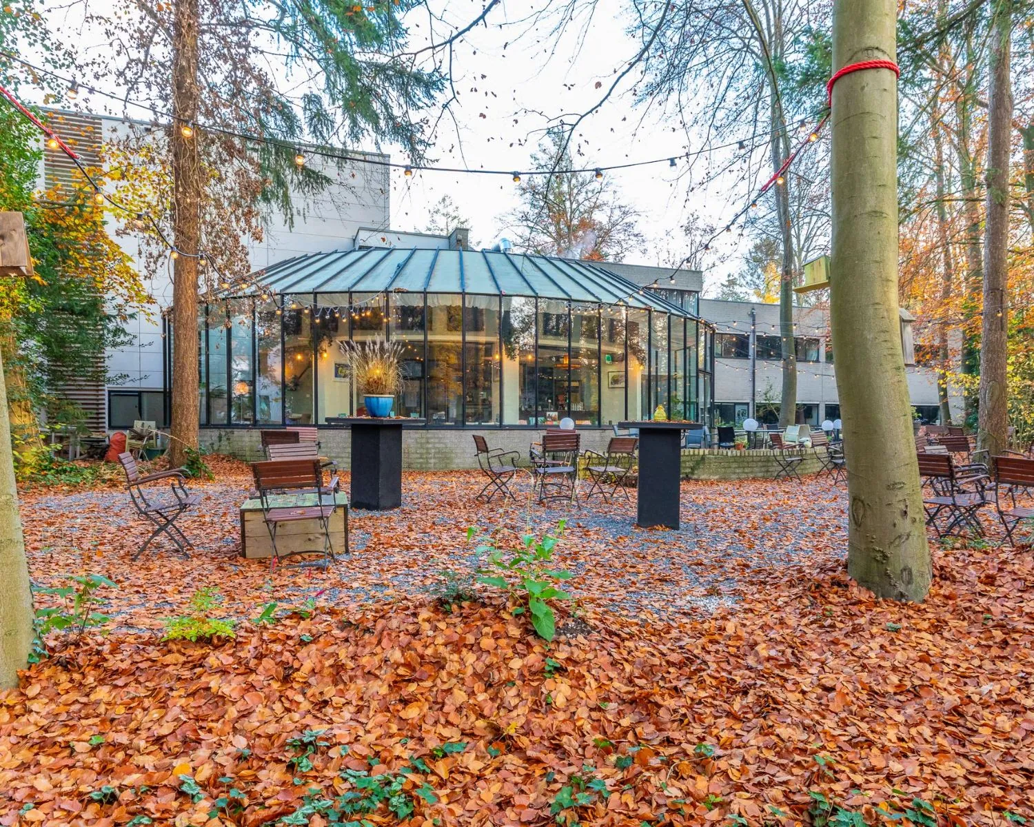 Herfstachtig buitenterrein met zitgelegenheden en glazen kantoorruimte aan de Mozartlaan 27 in Hilversum.