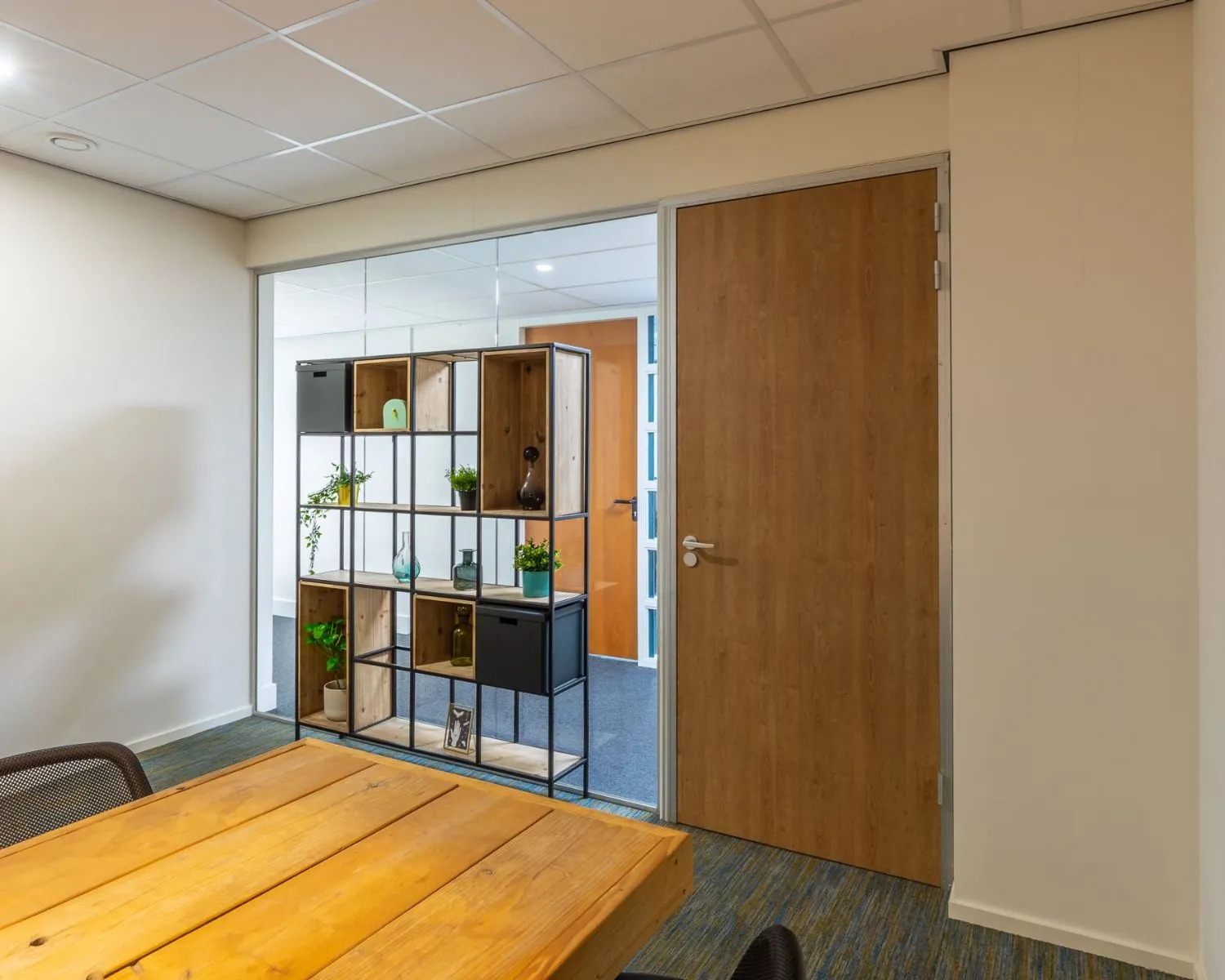 Moderne kantoorruimte aan de Mozartlaan 27 in Hilversum met houten vergadertafel en open stellingkast als ruimteverdeler.