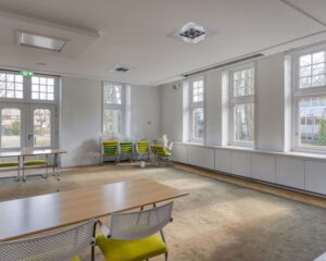 Lichte kantoorruimte met grote ramen, opklapstoelen en vergadertafels aan de Utrechtseweg 47 in Hilversum.