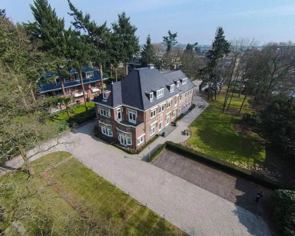 Vrijstaand kantoorpand aan de Utrechtseweg 47 in Hilversum, omgeven door groen en met ruime parkeergelegenheid.