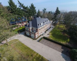 Vrijstaand kantoorpand aan de Utrechtseweg 47 in Hilversum, omgeven door groen en met ruime parkeergelegenheid.