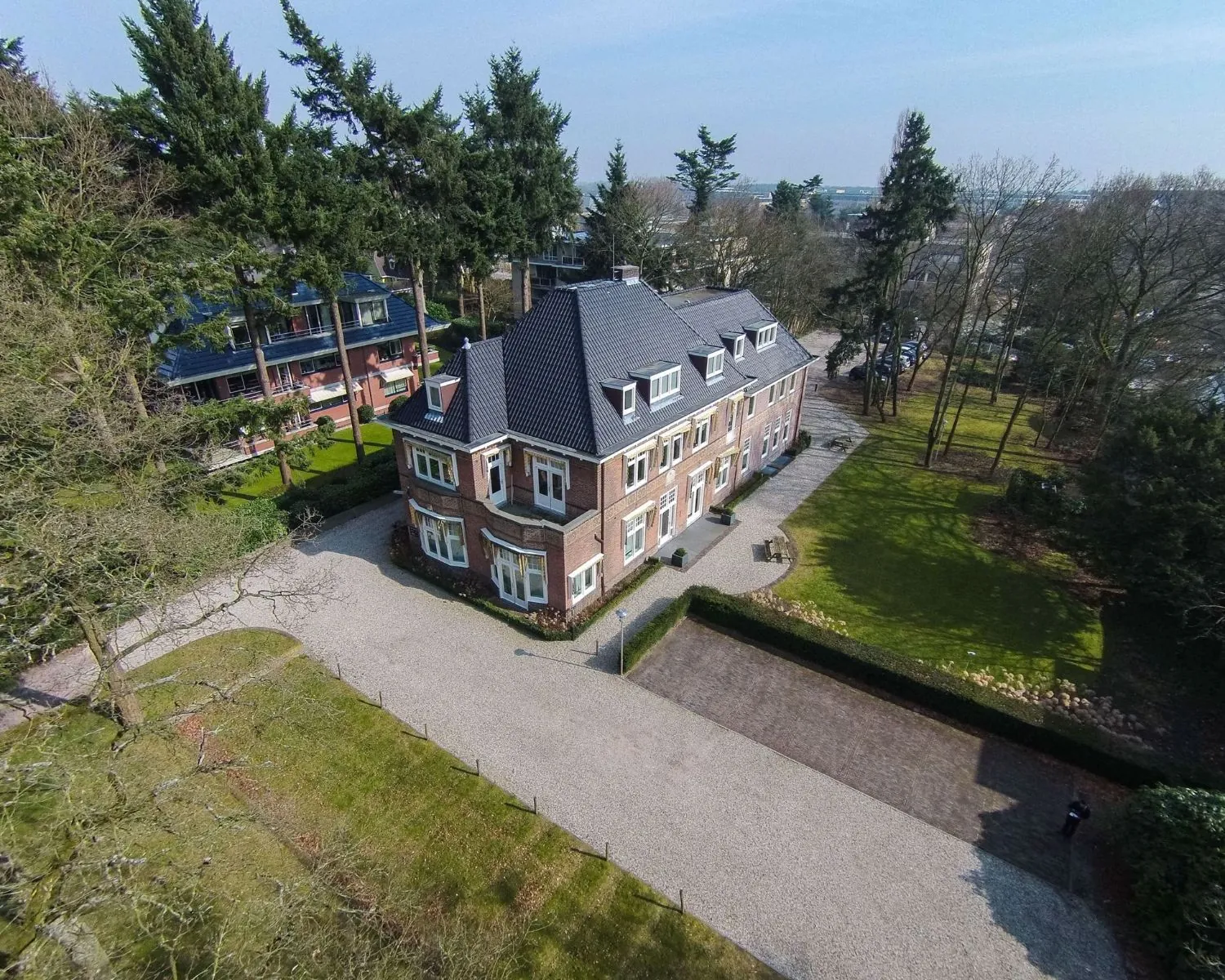 Vrijstaand kantoorpand aan de Utrechtseweg 47 in Hilversum, omgeven door groen en met ruime parkeergelegenheid.