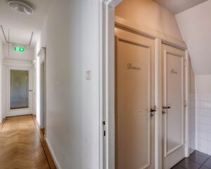 Gang in kantoorruimte aan de Utrechtseweg 47 in Hilversum met deuren naar dames- en herentoiletten.