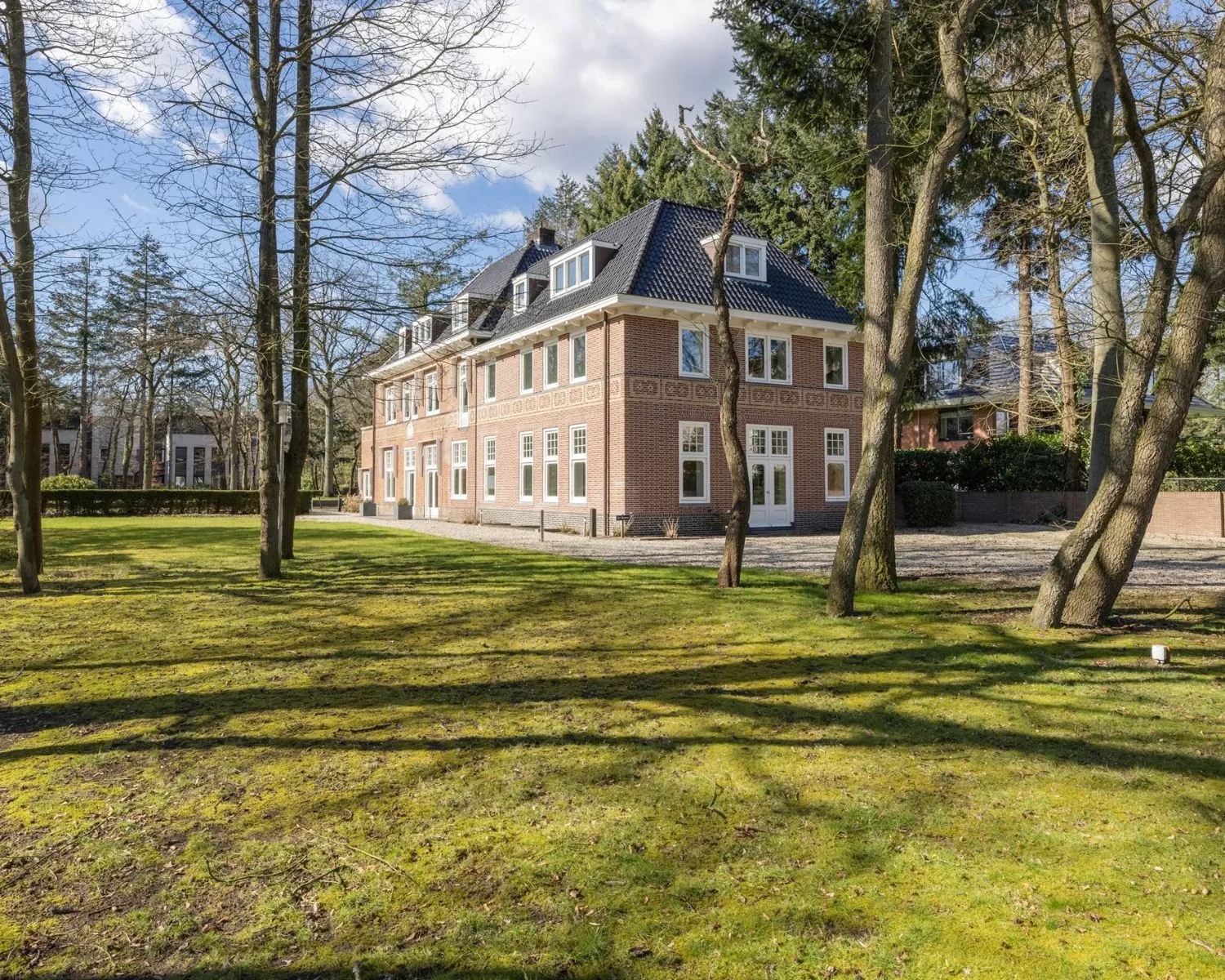 Vrijstaand kantoorvilla aan de Utrechtseweg 47 in Hilversum met ruime tuin en omringende bomen.